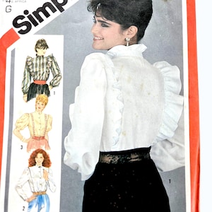Può includere: Modello di cucito Simplicity con una donna in una camicetta bianca con volant e una gonna nera. Il modello include illustrazioni di diversi stili di camicette e il testo "Simplicity".