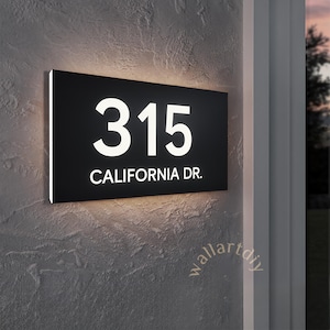 May include: A black rectangular house number sign with white illuminated numbers and text. The sign reads "315 CALIFORNIA DR."
