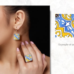 May include: A pair of earrings and a ring featuring a blue and yellow geometric tile pattern. The earrings are square shaped and dangle from a gold hoop. The ring is also square shaped and sits on the finger.