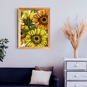 Puede incluir: Un cuadro enmarcado con una ilustraci&oacute;n de girasoles. La obra presenta flores amarillas y naranjas detalladas con hojas verdes sobre un fondo blanco. El marco es de madera clara, a&ntilde;adiendo un toque natural.