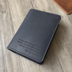 May include: A navy blue leather journal cover with stitched edges. The cover features an engraved quote: "My pen halts, though I do not Reader, you will walk no more with me. It is time we both take up our lives."