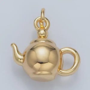 May include: A gold-colored teapot charm with a rounded body, curved spout, and a loop for hanging. The charm has a polished finish and a small handle. The teapot charm is a jewelry component.