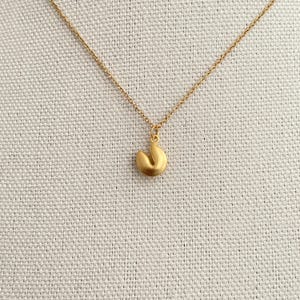 May include: A gold chain necklace with a gold fortune cookie charm.
