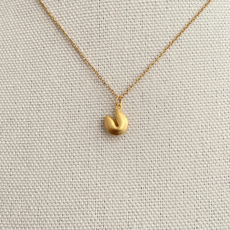 May include: A gold chain necklace with a gold fortune cookie charm.