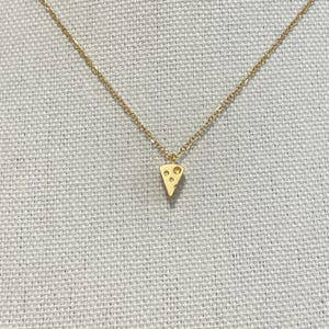 Peut inclure: Un collier en chaîne dorée avec un petit pendentif en or en forme de tranche de fromage suisse.