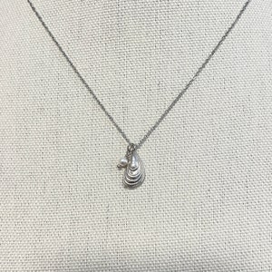 May include: A silver-toned necklace featuring a delicate chain and a pendant shaped like a small mussel shell. A tiny, round white pearl bead is attached to the jump ring next to the shell pendant, creating a simple and elegant accessory piece.