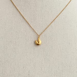 May include: A gold chain necklace with a gold fortune cookie pendant.