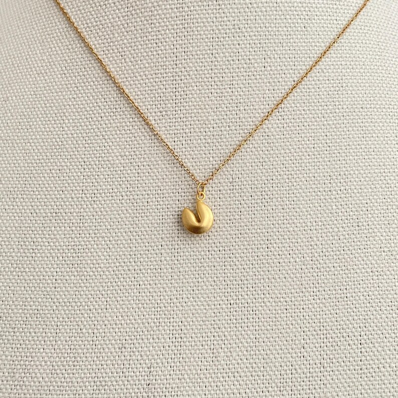 May include: A gold chain necklace with a gold fortune cookie pendant.