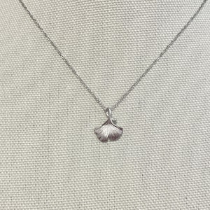 Puede incluir: Un collar de cadena de plata con un colgante de hoja de ginkgo.