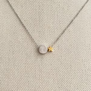 May include: A silver chain necklace with a small silver circle pendant and a gold star charm.
