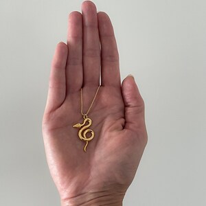 Žaltys Snake Necklace in gold in the palm of designer Jorie Breonn.