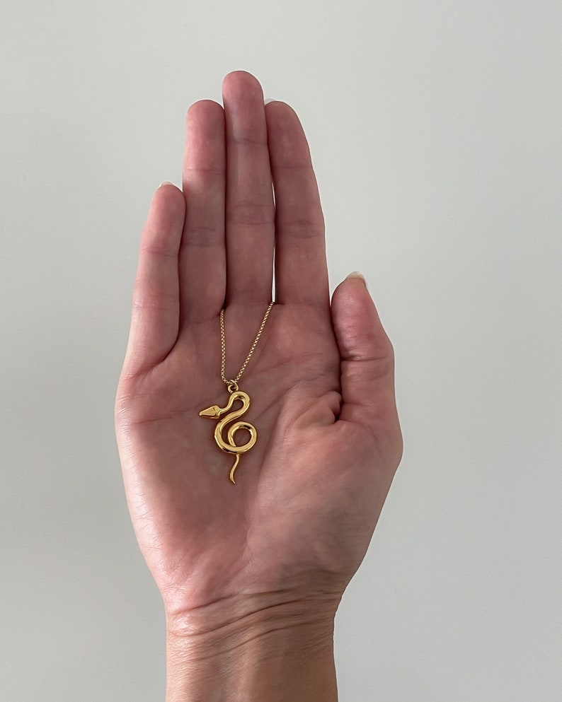 Žaltys Snake Necklace in gold in the palm of designer Jorie Breonn.