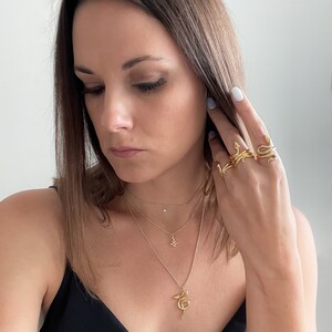 Starlight Layering Necklace, Vesta Goddess Layering Necklace, Žaltys Snake Necklace, and single, double, and triple wrapped Žaltys Snake Rings in gold on designer Jorie Breonn.