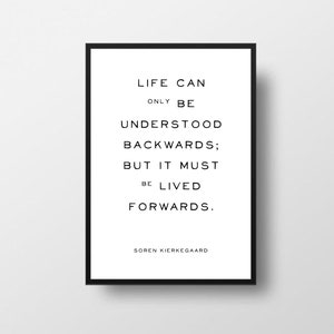 May include: Black and white typography print with the quote "Life can only be understood backwards; but it must be lived forwards." by Soren Kierkegaard.