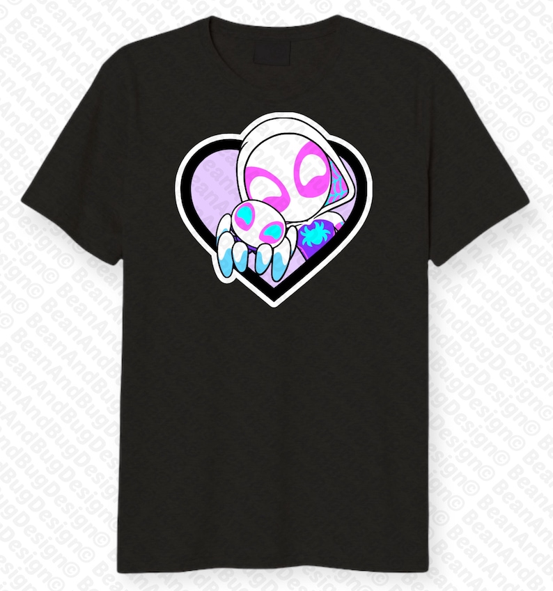 Op de afbeelding: Zwart T-shirt met een witte en roze hartvormige afbeelding met een wit en roze cartoonfiguur dat een kleiner blauw en roze cartoonfiguur vasthoudt.