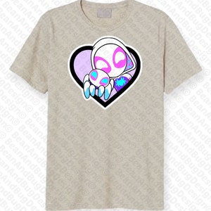 Op de afbeelding: Een lichtgrijs T-shirt met een afbeelding van een witte spinnenvrouw die een kleinere spin vasthoudt in een hartvormig frame. Het hart is zwart omrand en heeft een paarse en blauwe gradi&euml;nt aan de binnenkant.