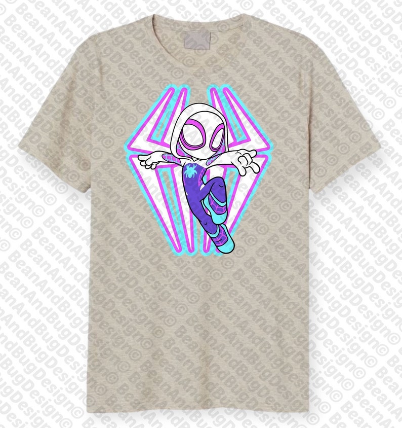 May include: A beige t-shirt with a graphic of a cartoon superhero in a white suit with purple and blue accents. The superhero is flying with a web design behind them.