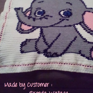 Puede incluir: Una manta de beb&eacute; de crochet blanco con un dise&ntilde;o de elefante gris y rosa. La manta tiene un borde rosa y el texto "Made by customer: Brenda Wallace" est&aacute; escrito debajo del elefante.