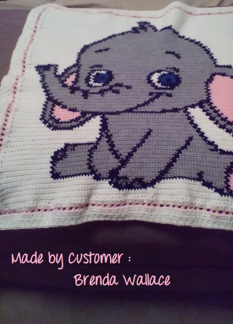 Puede incluir: Una manta de beb&eacute; de crochet blanco con un dise&ntilde;o de elefante gris y rosa. La manta tiene un borde rosa y el texto "Made by customer: Brenda Wallace" est&aacute; escrito debajo del elefante.