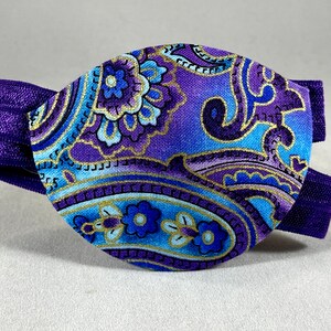 Pode incluir: Atadura para olho de paisley roxo e azul com uma faixa el&aacute;stica roxa.