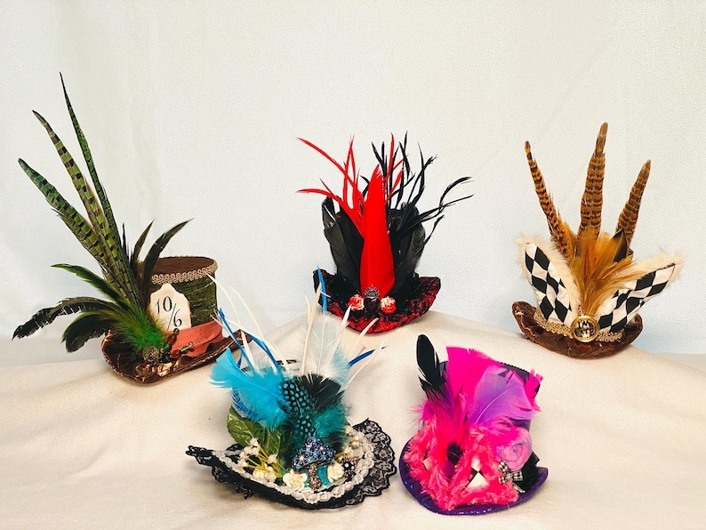 May include: Five miniature top hats with various embellishments, including feathers, fur, and lace. The hats are in different colors, including green, red, black, blue, and pink.