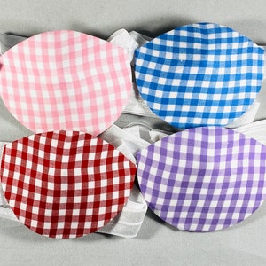 May include: Four eye patches with gingham patterns in pink, blue, red, and purple. Each patch is attached to a white elastic band.