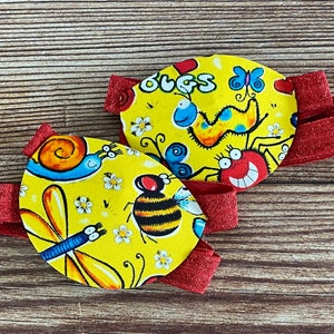 May include: Two yellow eye patches with red elastic bands. One patch features a bee, dragonfly, and snail. The other patch features a spider, butterfly, and caterpillar. The text "BUGS" is printed on the patch.
