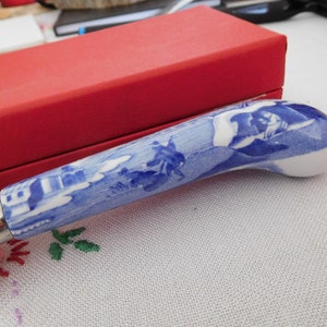 May include: A blue and white ceramic cake server with a decorative design. The server has a silver handle and a curved blade.