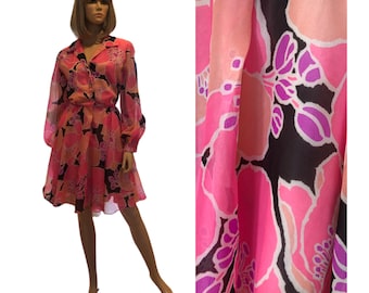 May include: A pink and black floral print mini dress with long sleeves and a collared neckline. The dress has a fitted bodice and a flowing skirt.