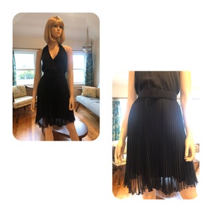 May include: A black pleated skirt with a matching halter top and a black belt with a silver buckle. The skirt is knee-length and has a sheer overlay.