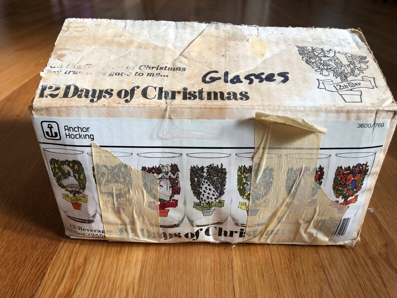 May include: A box of 12 Anchor Hocking "12 Days of Christmas" glasses. The box is white with red and black text. The glasses are clear with a festive design.