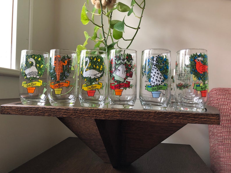 May include: Set of six clear glass tumblers with colorful illustrations of the 12 Days of Christmas. Each tumbler features a different day, with a festive design and the text "1st Day", "2nd Day", etc.