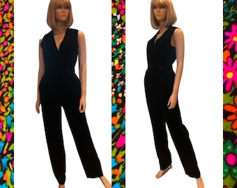 May include: A black velvet jumpsuit with a V-neck and sleeveless design. The jumpsuit has a button closure at the front and a belt.