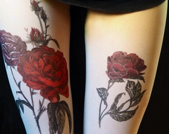 May include: A pair of white tights with a floral design. The design features two red roses and one purple rose with green leaves and stems.