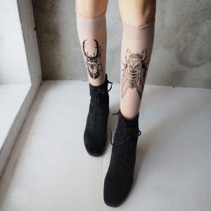 Hand-painted tattoo socks featuring intricate cicada and beetle artwork, perfect for entomology lovers, bug enthusiasts, and goblincore fashion. These unique, nature-inspired socks create a realistic tattoo illusion, combining art and style in wearable form. A thoughtful and quirky insect-themed gift for those who appreciate novelty and handcrafted designs.