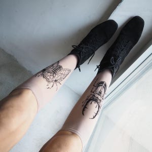Hand-painted tattoo socks featuring intricate cicada and beetle artwork, perfect for entomology lovers, bug enthusiasts, and goblincore fashion. These unique, nature-inspired socks create a realistic tattoo illusion, combining art and style in wearable form. A thoughtful and quirky insect-themed gift for those who appreciate novelty and handcrafted designs.