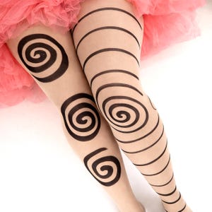 Könnte beinhalten: Hautfarbene transparente Strumpfhose mit schwarzen Spiral- und Streifenmustern. Die Strumpfhose hat große Spiralmuster auf den Oberschenkeln und horizontale Streifen auf den Unterschenkeln. Im Hintergrund ist ein rosa Tüllrock zu sehen.