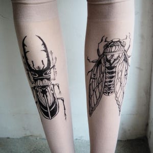 Hand-painted tattoo socks featuring intricate cicada and beetle artwork, perfect for entomology lovers, bug enthusiasts, and goblincore fashion. These unique, nature-inspired socks create a realistic tattoo illusion, combining art and style in wearable form. A thoughtful and quirky insect-themed gift for those who appreciate novelty and handcrafted designs.