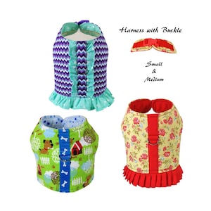 May include: Three dog harnesses with buckle closures. One is purple and teal chevron with ruffles. Another is green with a dog and house pattern. The third is yellow with red roses and a red ruffle. Text reads "Harness with Buckle" and "Small & Medium".