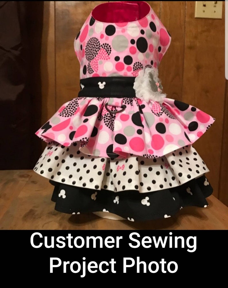May include: A tiered dog dress featuring a pink, black, and white polka dot design. It has a black belt with a Mickey Mouse emblem and a white flower. The text "Customer Sewing Project Photo" is displayed at the bottom.