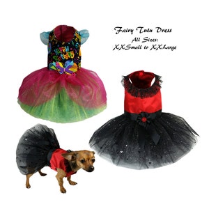 May include: Two fairy tutu dresses for dogs. One is pink and green with a "Happy Birthday" print and the other is black with red trim. A small dog is wearing a black tutu dress with red trim.