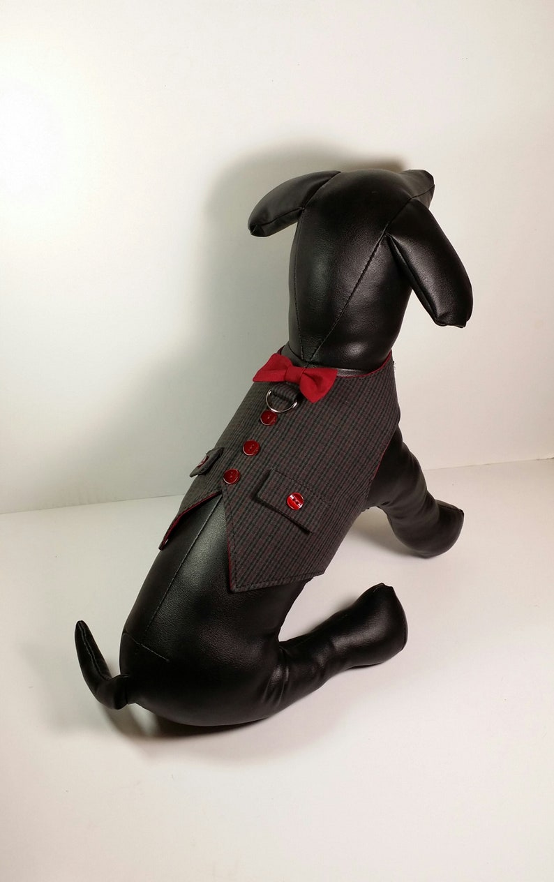 Puede incluir: Un maniqu&iacute; de perro negro que lleva un chaleco de patr&oacute;n gris y negro con ribetes rojos y una pajarita roja. El chaleco tiene un bolsillo en la parte delantera y botones rojos.