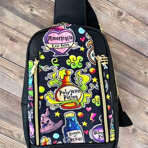 May include: A black faux leather crossbody bag with a colorful, printed fabric lining. The lining features various potion bottles, hearts, stars, and the text "Amortentia Love Potion", "Polyjuice Potion", "Draught of Peace", and "Sleep Drink".