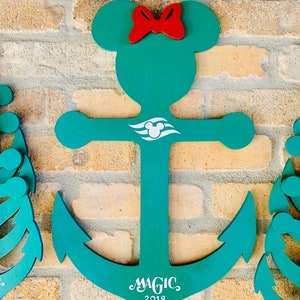 May include: A teal blue anchor with a red bow and Mickey Mouse ears. The anchor has a white Disney cruise line logo and the text "MAGIC 2019" on the bottom.