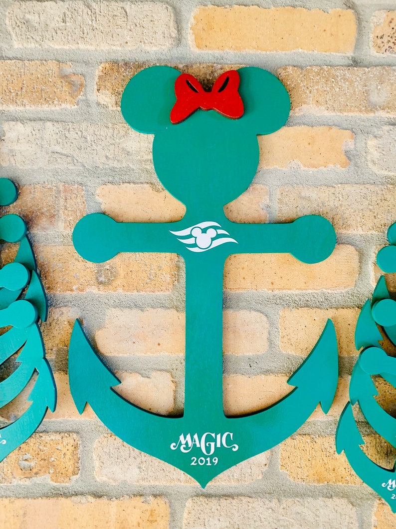 May include: A teal blue anchor with a red bow and Mickey Mouse ears. The anchor has a white Disney cruise line logo and the text "MAGIC 2019" on the bottom.