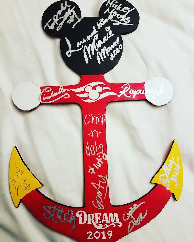 May include: A red wooden anchor with a Mickey Mouse head at the top. The anchor is decorated with silver glitter and has the words "Stitch Dream 2019" written on it. The anchor is signed by various Disney characters, including Mickey Mouse, Minnie Mouse, Cinderella, Rapunzel, Chip, Dale, Pluto, Goofy, and others.