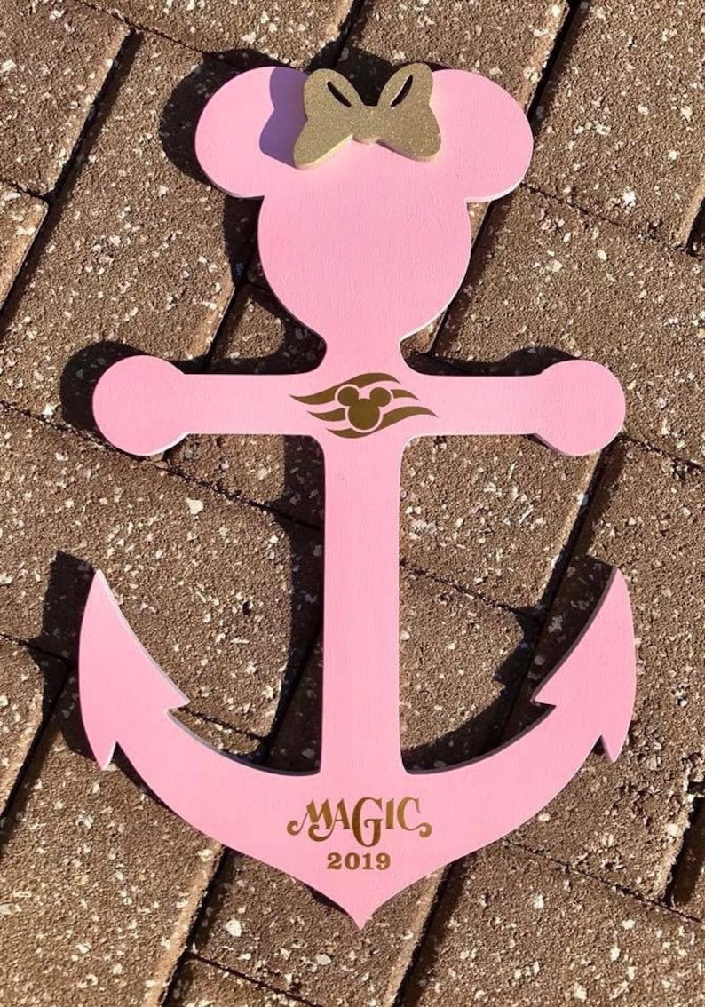 May include: Pink wooden anchor with a gold Mickey Mouse head and bow on top. The anchor has a gold Disney Cruise Line logo and the text "MAGIC 2019" on the bottom.