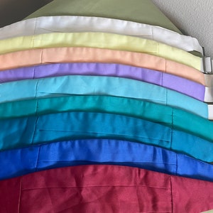 May include: A set of 10 bow ties in various colors, including white, yellow, peach, lavender, light blue, teal, blue, and burgundy. The bow ties are arranged in a rainbow pattern.