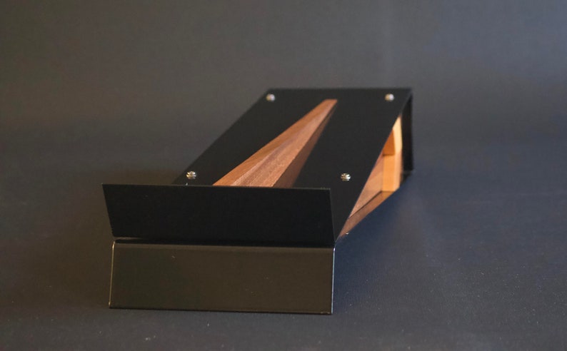 May include: A black metal stand with a wooden insert. The stand is angled and has a flat surface.