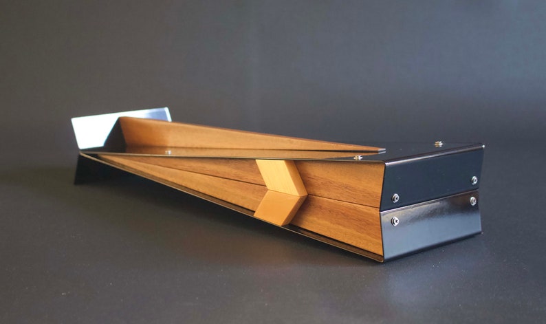 May include: A wooden chopstick holder with a black metal frame. The holder is angled and has a modern design.